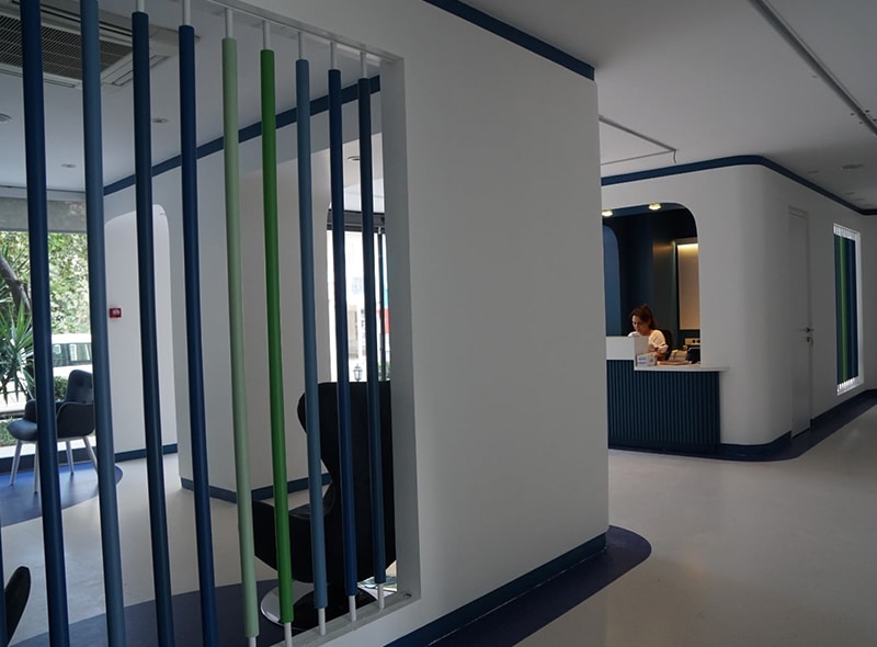 AsyaKBB - Ana Sayfa 9 Asya KBB kliniğinde mavi çizgili bölmelerin bulunduğu koridor ve karşılama masası