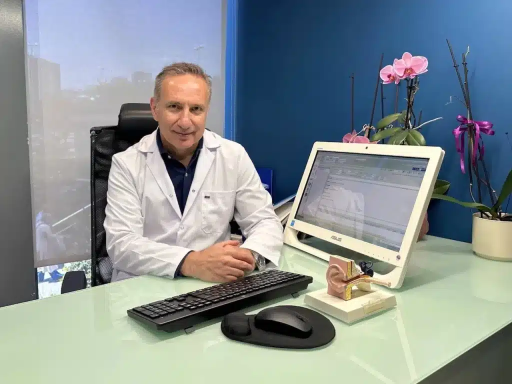 Op. Dr. Fuat Güder, Asya KBB Kliniği'ndeki muayene odasında masasında otururken